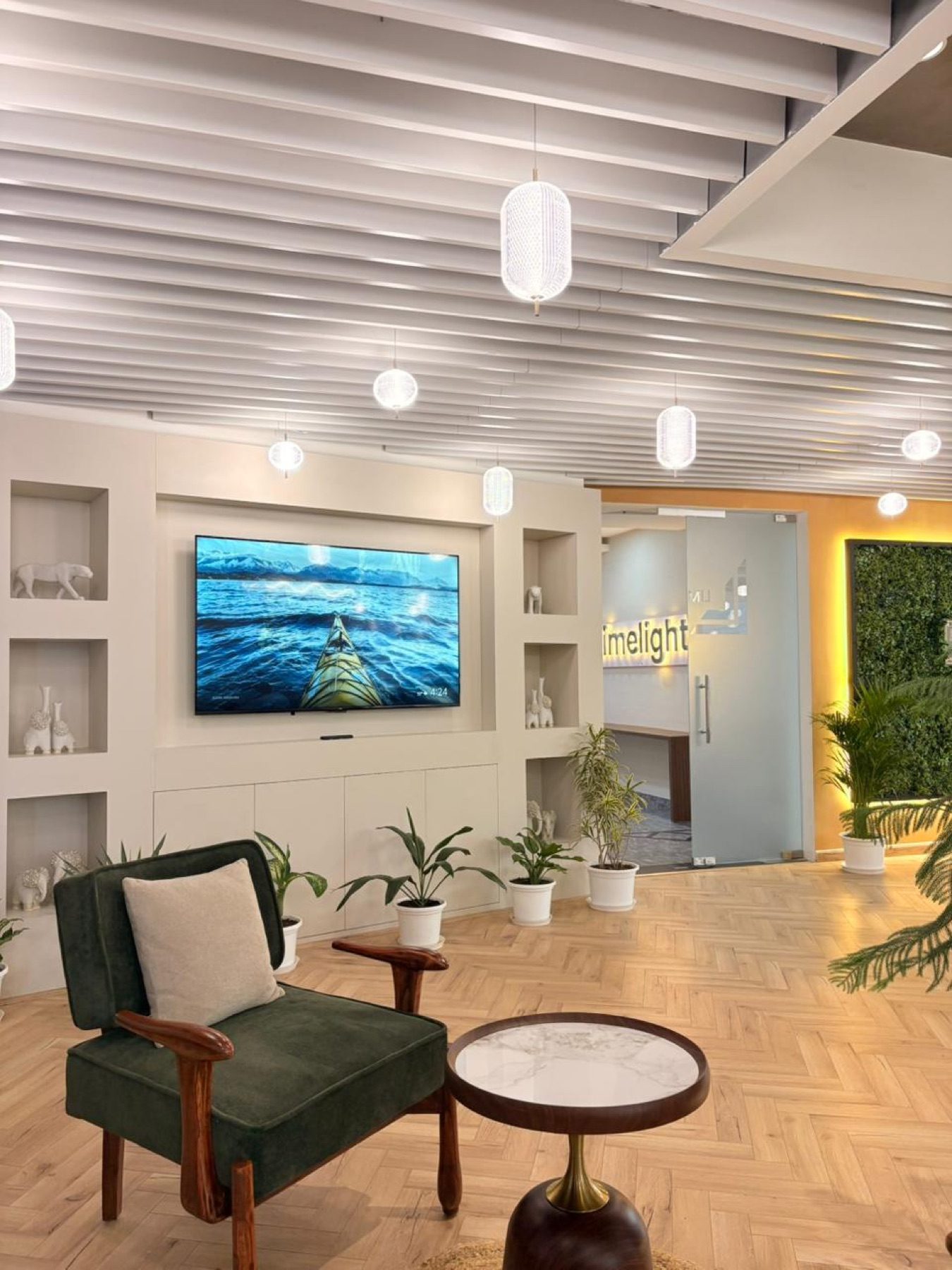 Entry lounge at Limelight Coworks with soft seating, wall display, plants, and branded glass doors