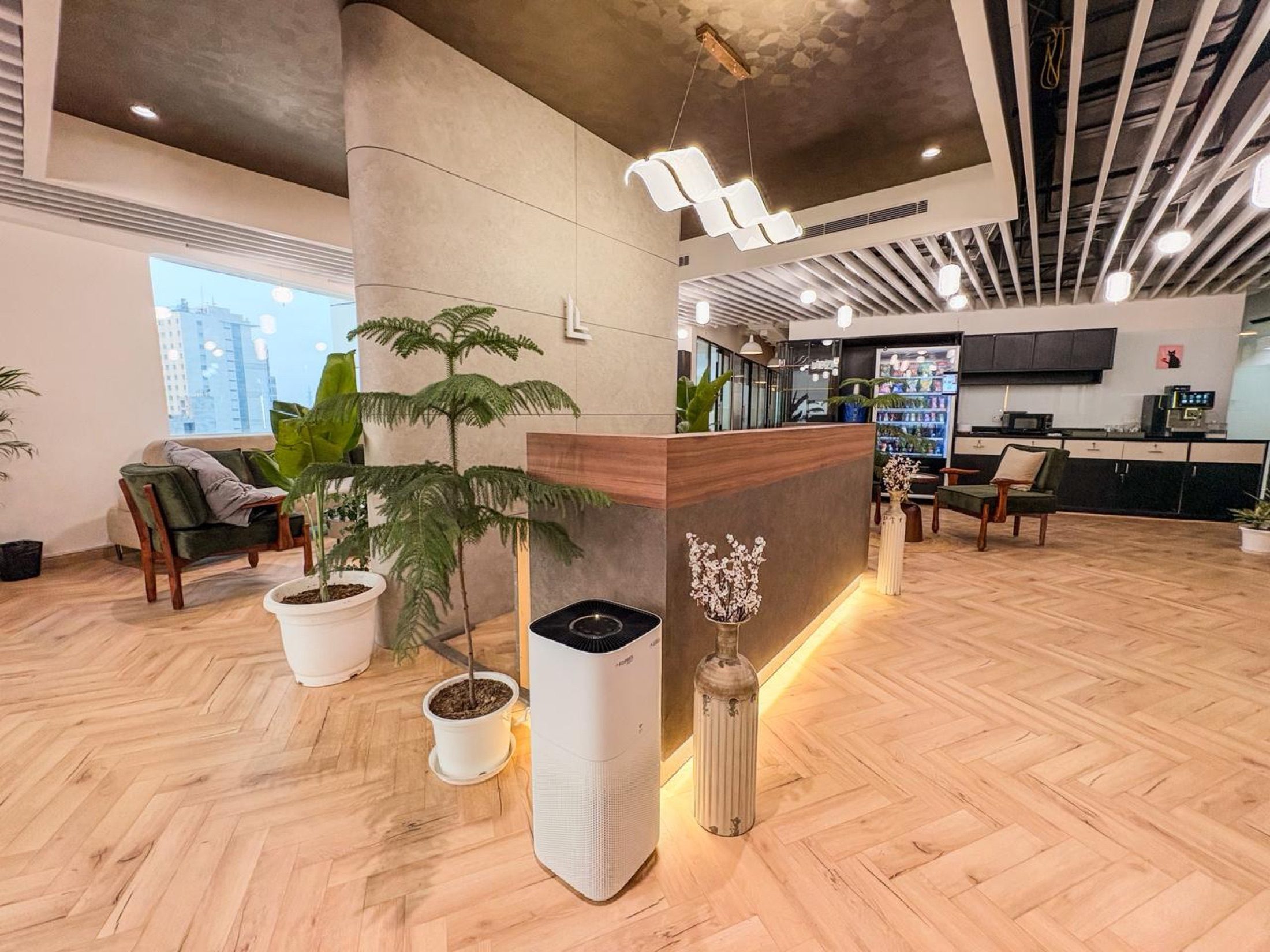 Warm reception lounge at Limelight Coworks with plants, wood flooring, and the front desk